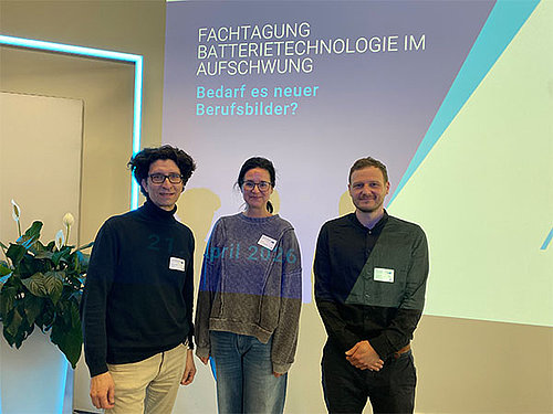 Bild von Jana Ellinger, Projektleiterin von Batterieverbund BatterieMD und Matthias Geisthardt (Projektleitung) & Sebastian Rödel (Projektberatung) von KOMBiH vor der Leinwand der Fachtagung.